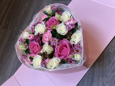 Pink Heart Surprise - This beautifully presented Heart shaped box arrives closed and then open up to reveal a lovely arrangement of fresh flowers. The sides then fold back to angle the box to show of the beautiful arrangement. The standard includes Roses and other seasonal flowers.