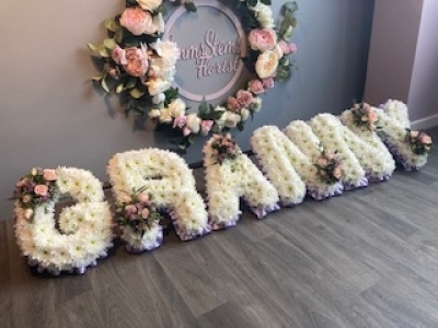 GRANNY - GRANNY - Arranged with a lovely lilac ribbon edge, white base flowers and soft pink roses in the letter sprays.