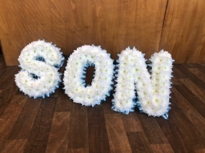 SON - SON Letters arranged with a pale blue ribbon edge with white based flowers. This can be made in your own choice of flowers and can also have added flower sprays onto the letters if you wish.