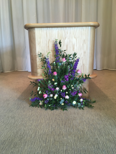 Catafault Arrangement - Made for Cromer Crematorium at the base of the Catafault this narrow thin Seasonal Arrangement sits on the floor and allows the curtain to pass if you wish. Also adding that much needed colour on a sad day.