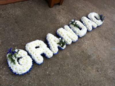 Grandad Letter Tribute - Based in White Chrysanthemums with a Blue Ribbon edge, finished with Blue and White Sprays of Flowers to complete this lovely Tribute.