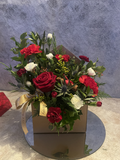 Letter to Santa - A charming envelope-style arrangement filled with vibrant red blooms, fresh greenery, and seasonal accents. The perfect way to share Christmas joy in a truly unique design.