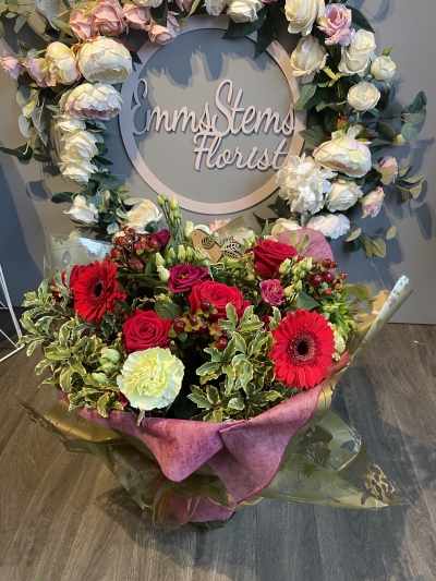 Joy of Christmas - Seasonal Flowers in tones of rich Reds & Greens. Arranged in a lovely hand tie arrangement and gift wrapped in luxury wrapping.